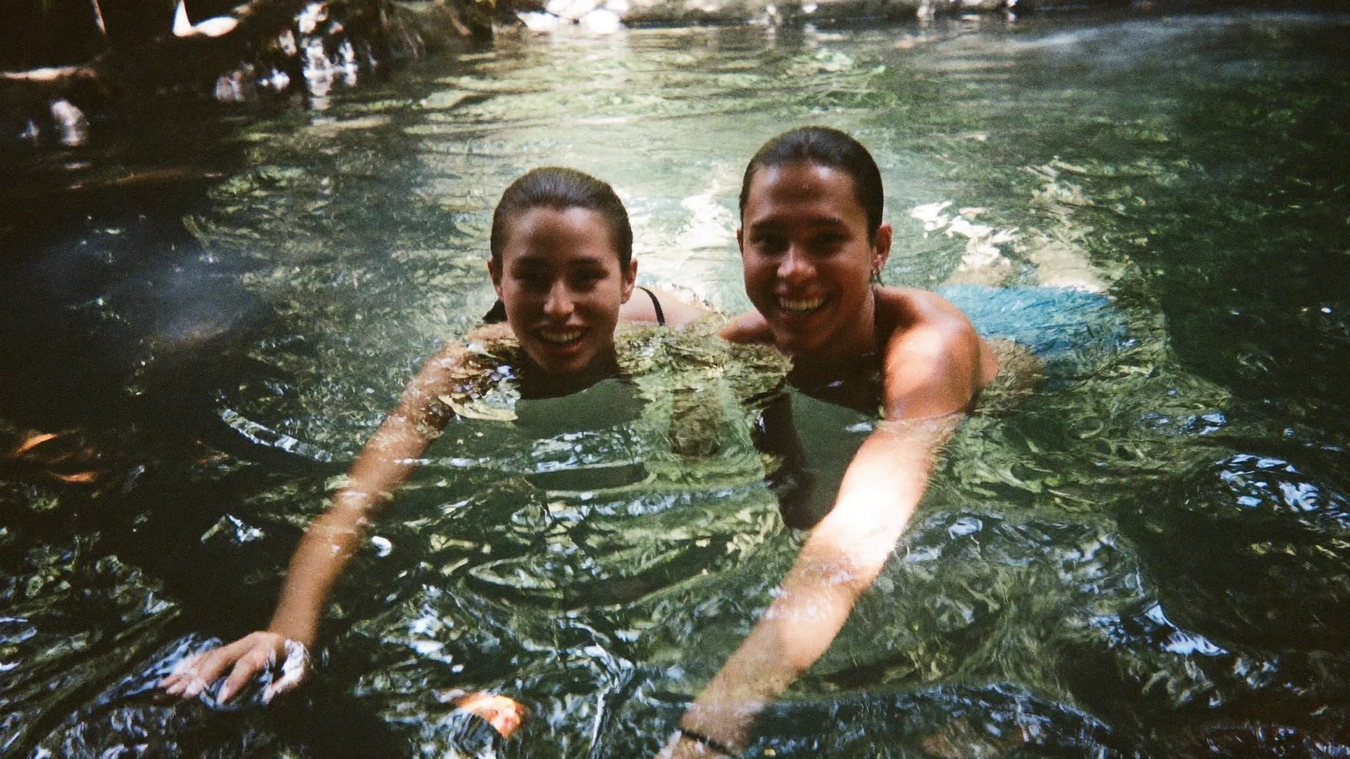 Dos visitantes en el agua de un cenote de la selva cerca de Tulum